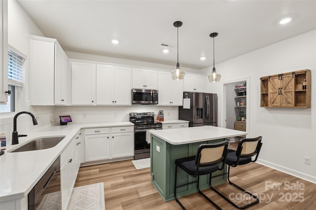 104 Trellis Ln, Troutman, NC 28166 - kitchen featuring stainless steel appliances, a sink, white cabinets, light wood-type flooring, and a kitchen bar