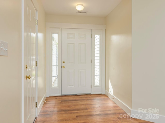 foyer featuring visible vents, baseboards, and wood finished floors