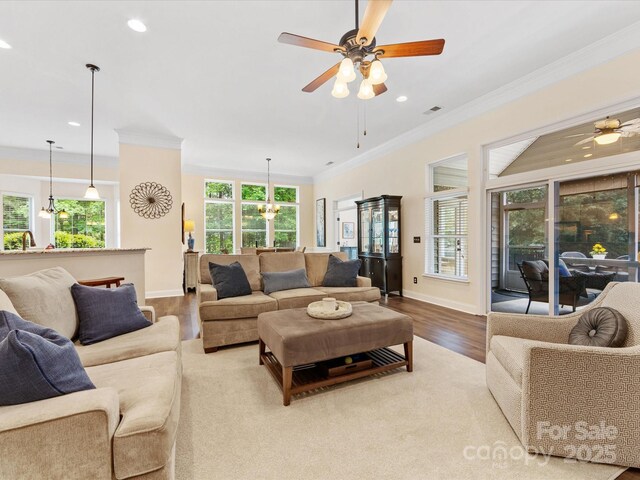 living area featuring wood finished floors, a ceiling fan, visible vents, ornamental molding, and recessed lighting