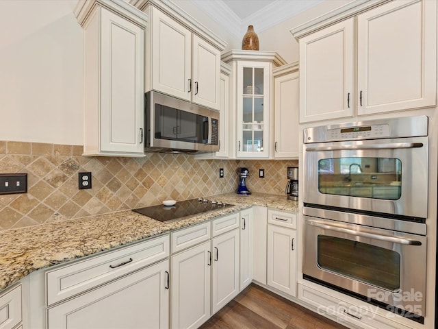 kitchen with glass insert cabinets, stainless steel appliances, crown molding, tasteful backsplash, and light stone counters