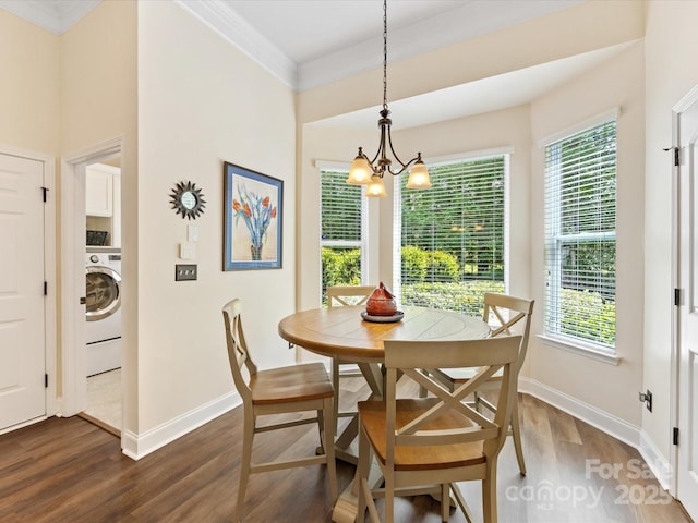 dining room featuring plenty of natural light, washer / dryer, a chandelier, crown molding, and dark wood-type flooring