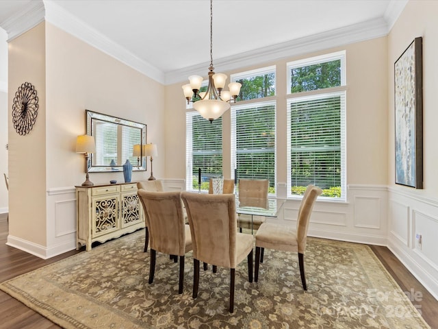 dining area with ornamental molding, a notable chandelier, wainscoting, and wood finished floors