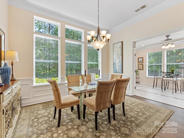 dining space featuring a healthy amount of sunlight, an inviting chandelier, ornamental molding, and visible vents
