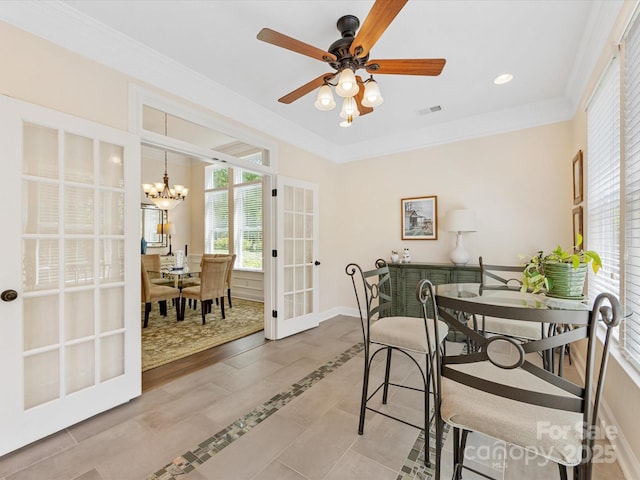 dining area featuring french doors, baseboards, visible vents, ceiling fan with notable chandelier, and crown molding