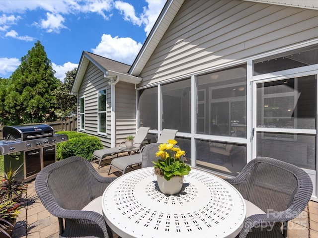 view of patio / terrace with a sunroom, area for grilling, and outdoor dining area