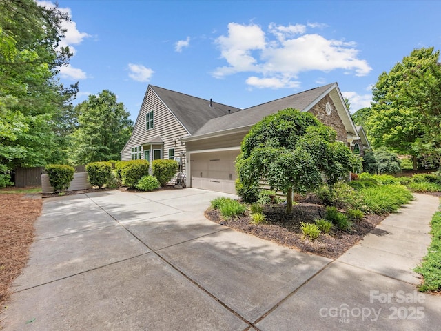 view of side of home with concrete driveway, an attached garage, and fence