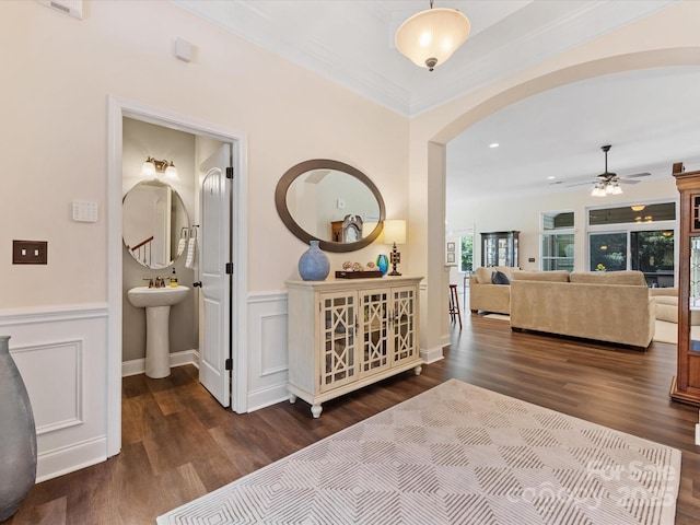 hallway with wood finished floors, a sink, a wainscoted wall, arched walkways, and recessed lighting