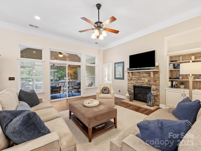 living room featuring crown molding, a ceiling fan, visible vents, and wood finished floors