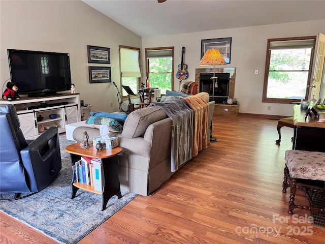 5A Hedgerose Ct, Asheville, NC 28805 - living room featuring baseboards, a fireplace with raised hearth, a ceiling fan, light wood finished floors, and vaulted ceiling