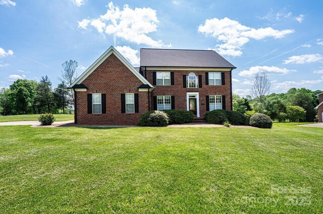 colonial inspired home with brick siding and a front lawn