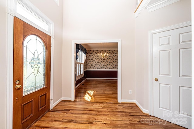 entrance foyer with baseboards, plenty of natural light, wood finished floors, and a notable chandelier