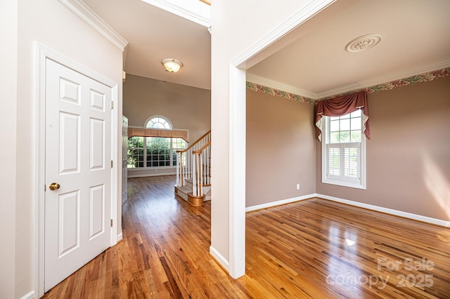 entrance foyer with crown molding, wood finished floors, and a healthy amount of sunlight