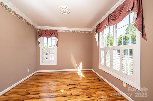 empty room with baseboards, ornamental molding, and light wood finished floors