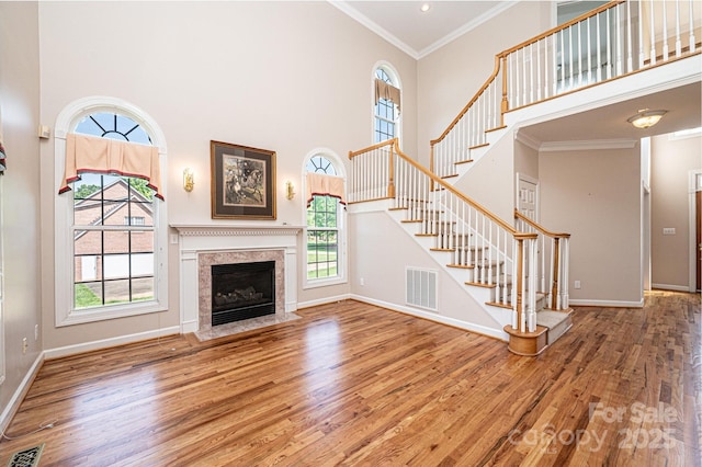 unfurnished living room with visible vents, a towering ceiling, and wood finished floors