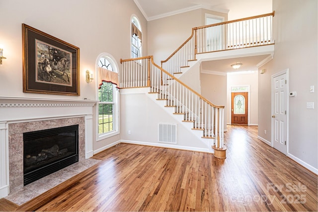 unfurnished living room with wood finished floors, ornamental molding, and a high ceiling
