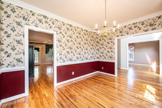 unfurnished room with an inviting chandelier, crown molding, baseboards, wallpapered walls, and light wood-type flooring