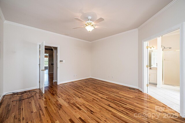 empty room featuring crown molding, baseboards, ceiling fan, and light wood finished floors