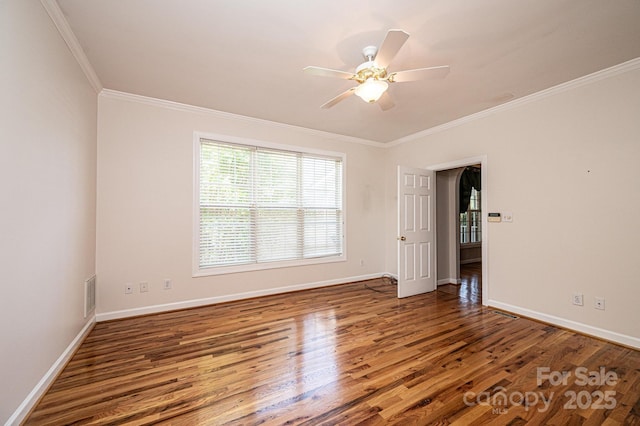 unfurnished room with crown molding, baseboards, visible vents, and wood finished floors