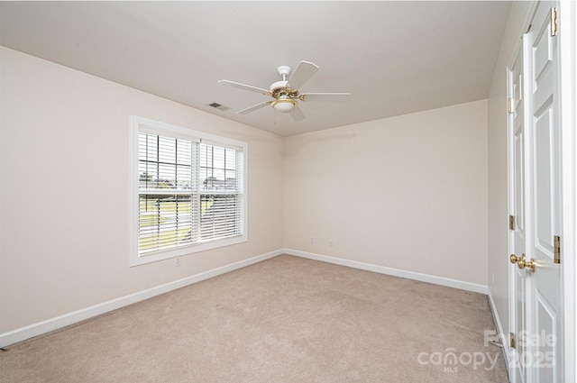spare room with light colored carpet, baseboards, visible vents, and ceiling fan
