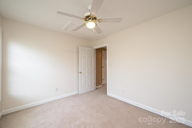 unfurnished room with baseboards, light carpet, a ceiling fan, and attic access