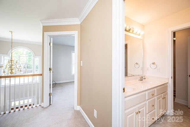 bathroom with crown molding, double vanity, baseboards, a sink, and a notable chandelier