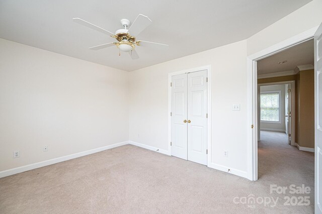 unfurnished bedroom featuring baseboards, crown molding, a closet, and light carpet