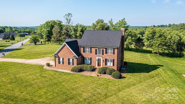 colonial house with a chimney, a front lawn, and brick siding
