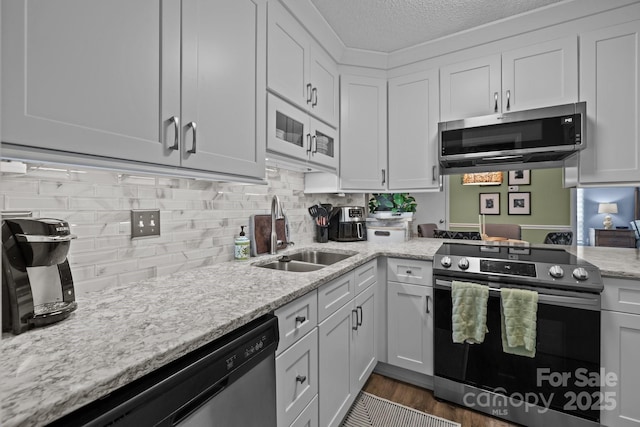 kitchen featuring backsplash, a textured ceiling, a sink, stainless steel appliances, and white cabinetry