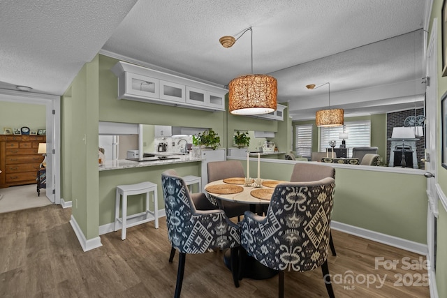 dining room with baseboards, a textured ceiling, and wood finished floors