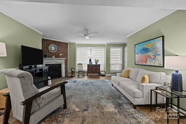 living room with crown molding, a ceiling fan, a textured ceiling, and a fireplace
