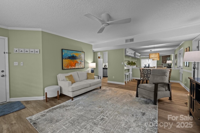 living room featuring ceiling fan, a textured ceiling, visible vents, and wood finished floors