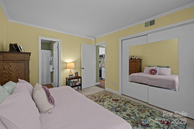 bedroom featuring visible vents, ornamental molding, carpet, and ensuite bath