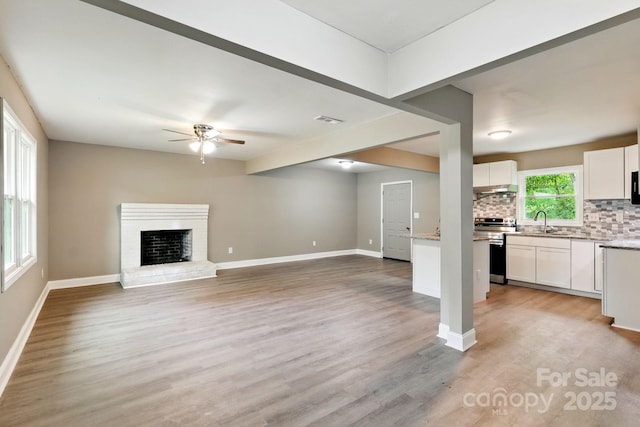 131 Little Forest Ln, Statesville, NC 28625 - unfurnished living room with visible vents, baseboards, ceiling fan, a sink, and light wood-style flooring