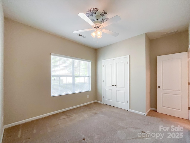 unfurnished bedroom featuring carpet flooring, ceiling fan, baseboards, visible vents, and a closet