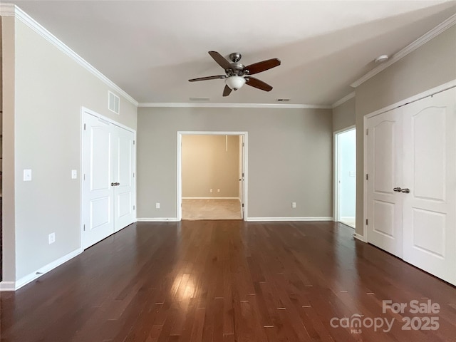 unfurnished bedroom with dark wood-style flooring, baseboards, visible vents, and ornamental molding