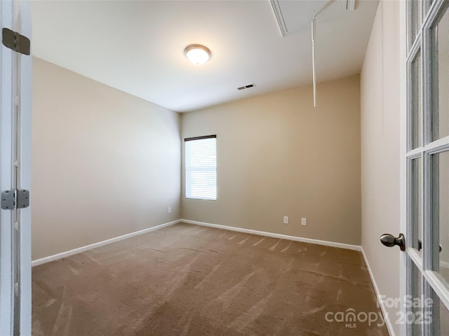 unfurnished room featuring visible vents, baseboards, carpet, and attic access