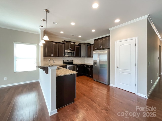 kitchen featuring ornamental molding, a peninsula, dark brown cabinets, light stone counters, and stainless steel appliances