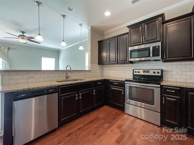 kitchen with ornamental molding, a peninsula, a sink, backsplash, and stainless steel appliances