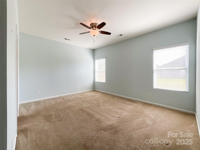 carpeted spare room featuring ceiling fan, visible vents, and baseboards