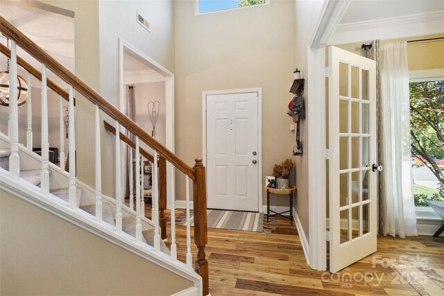 7700 Ninth Fairway Ln, Mint Hill, NC 28227 - entryway featuring crown molding, stairs, wood finished floors, a towering ceiling, and visible vents