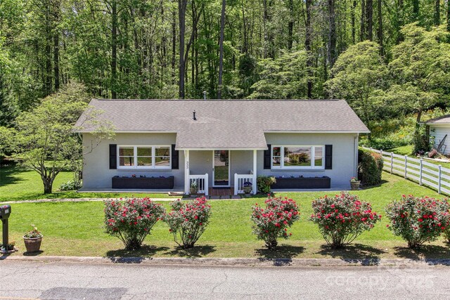 ranch-style home with fence, a shingled roof, a front lawn, brick siding, and a porch