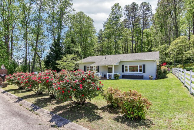 ranch-style home featuring fence and a front lawn