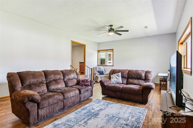 living room featuring a textured ceiling, ceiling fan, visible vents, and wood finished floors
