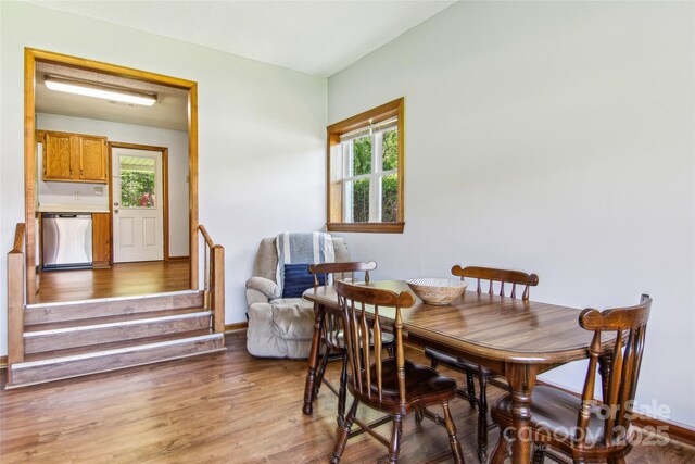 dining space featuring stairway, baseboards, and light wood finished floors