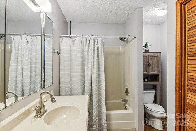 full bathroom featuring toilet, a textured ceiling, shower / bath combo with shower curtain, and vanity