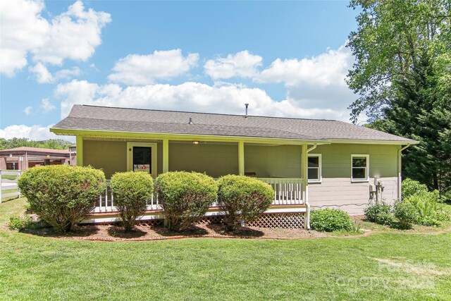 rear view of property with a lawn, a porch, and roof with shingles