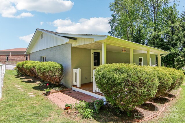 view of home's exterior featuring a lawn, fence, and brick siding