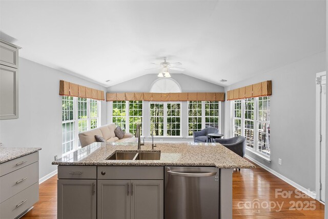kitchen featuring gray cabinets, a ceiling fan, stainless steel dishwasher, a sink, and open floor plan