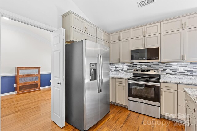 kitchen with stainless steel appliances, visible vents, decorative backsplash, and light wood-style floors