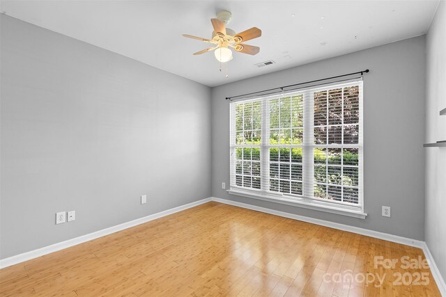 unfurnished room with a ceiling fan, baseboards, visible vents, and wood finished floors